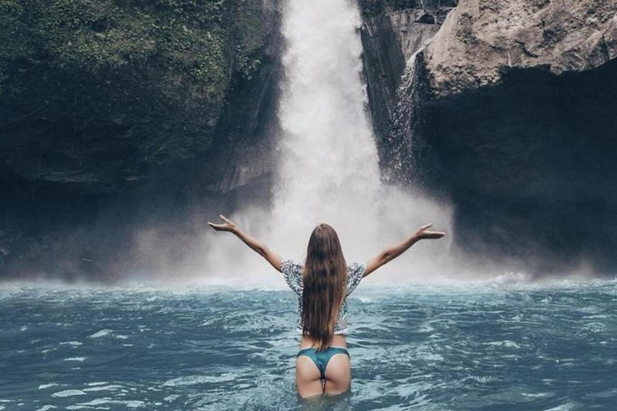 kona í vatninu fyrir framan foss