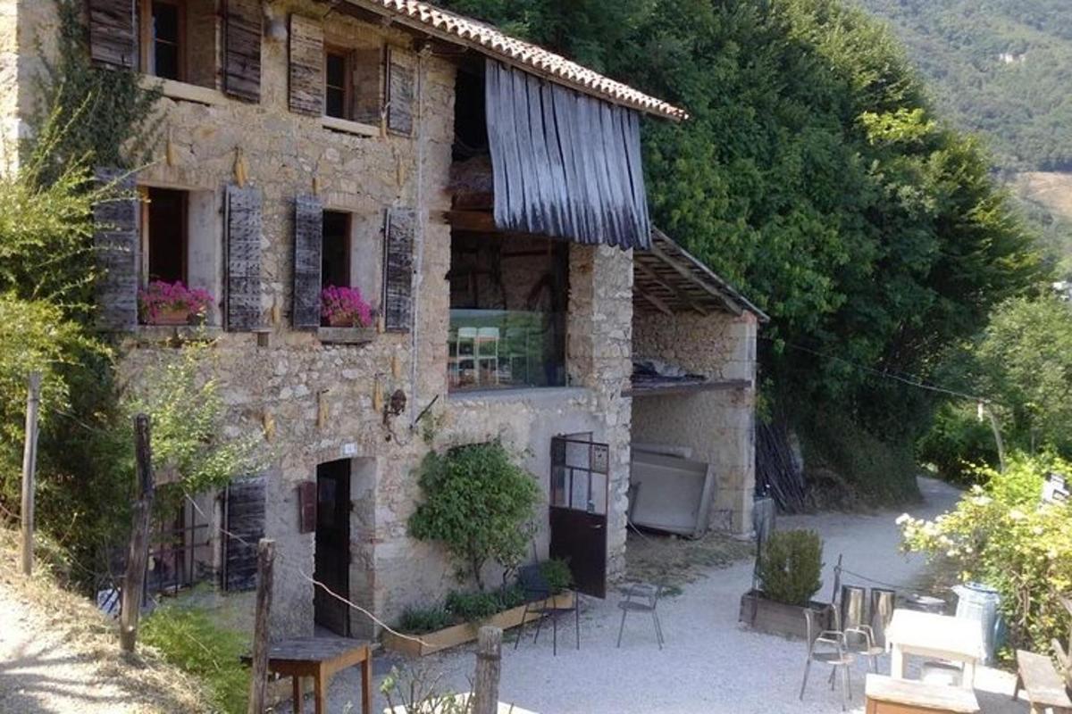 una antiga casa de pedra amb taules i cadires al davant