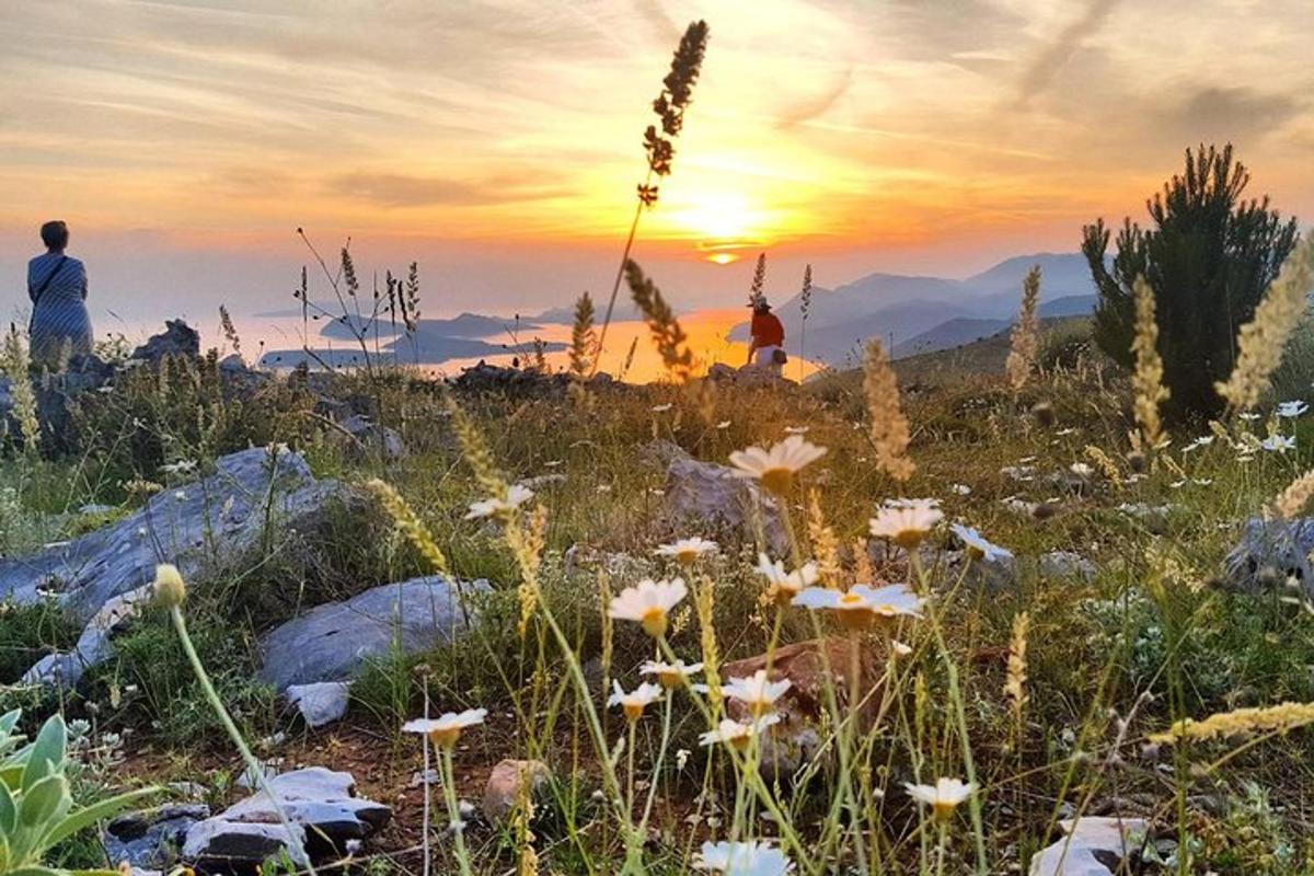 seorang lelaki duduk di atas gunung pada waktu matahari terbenam