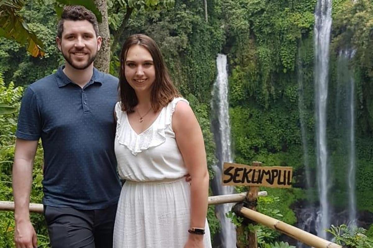 um homem e uma mulher em pé em frente a uma cachoeira