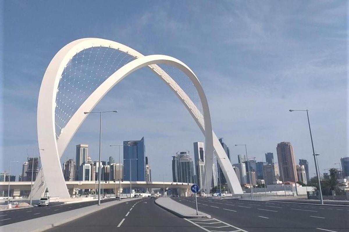 جسر قوسي أبيض فوق طريق سريع مع مدينة