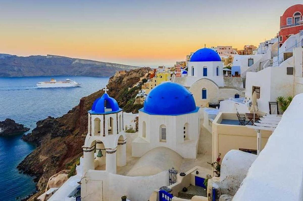 um grupo de edifícios com cúpulas azuis e o oceano