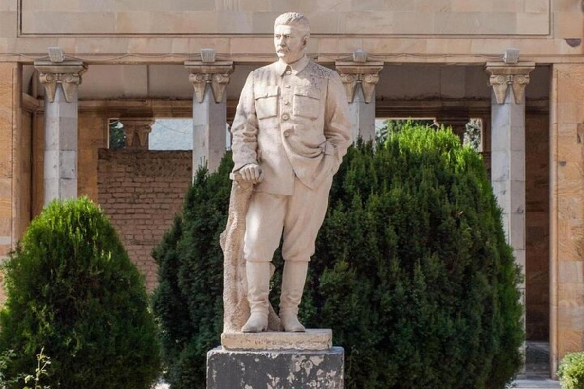 una statua di un uomo in giacca e cravatta davanti a un edificio