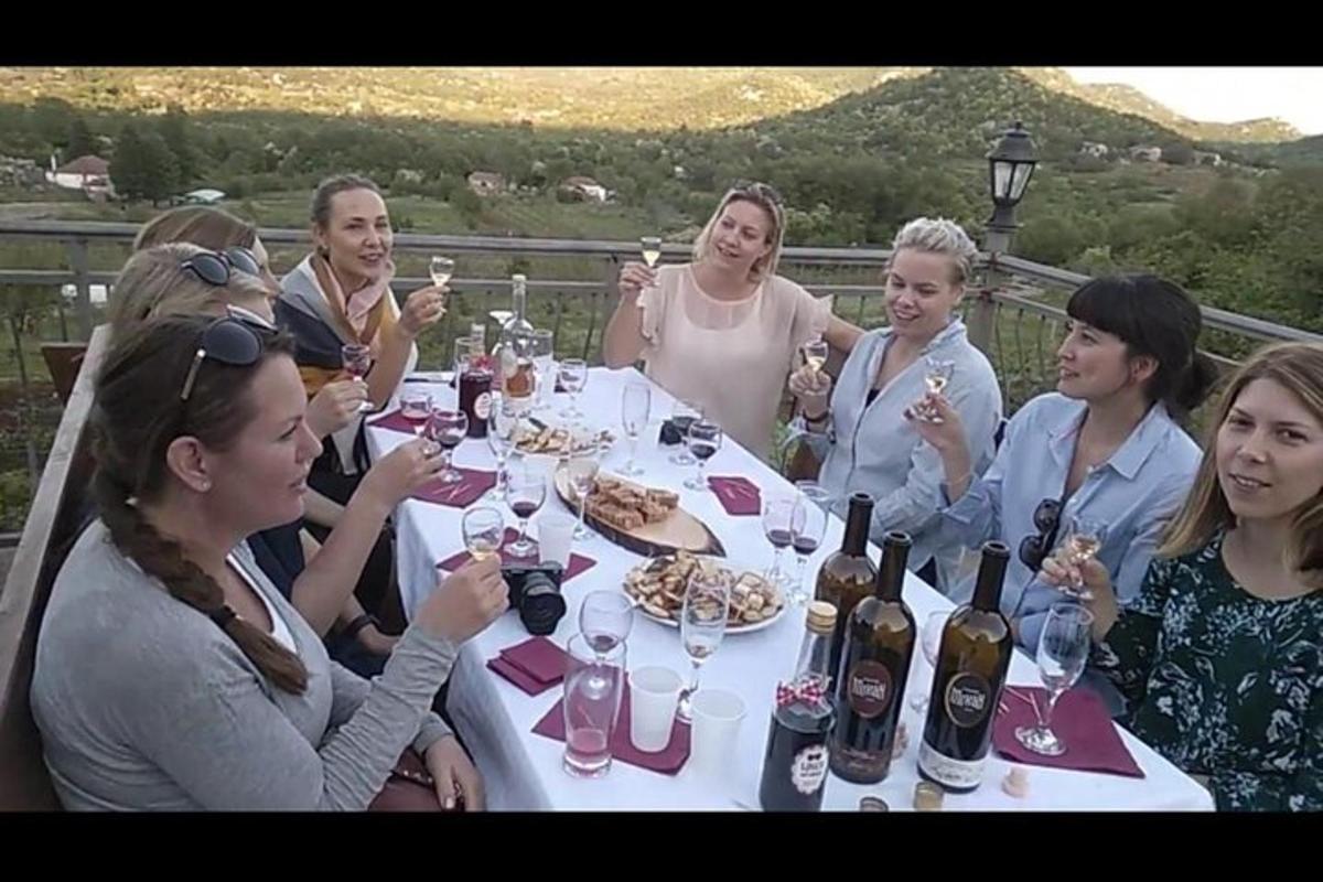 skupina ljudi, ki sedijo okoli mize s steklenicami vina