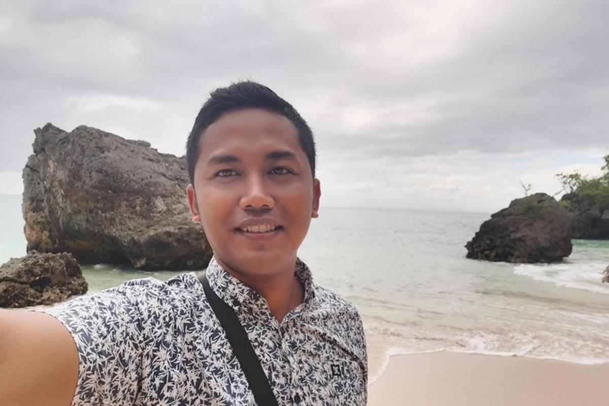 seorang lelaki berdiri di pantai berhampiran lautan