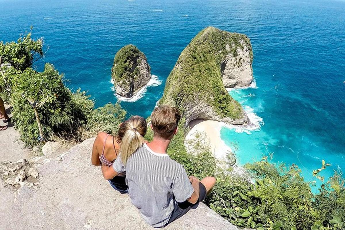 un uomo e una donna seduti su una roccia che domina l'oceano