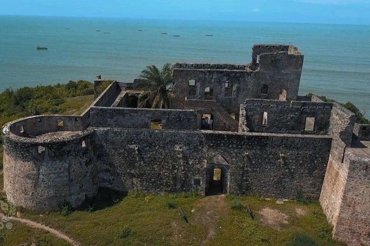 starý hrad na kopci s oceánem za ním