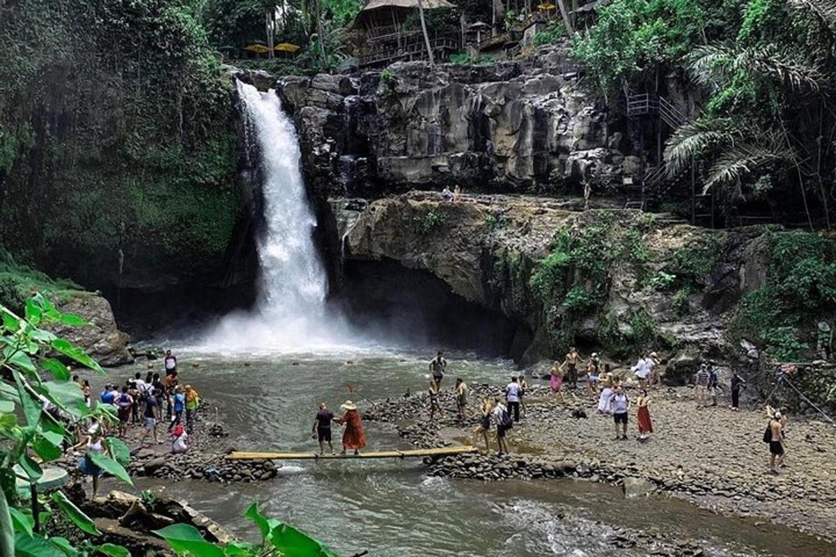 Eine Gruppe von Menschen steht an einem Strand in der Nähe eines Wasserfalls