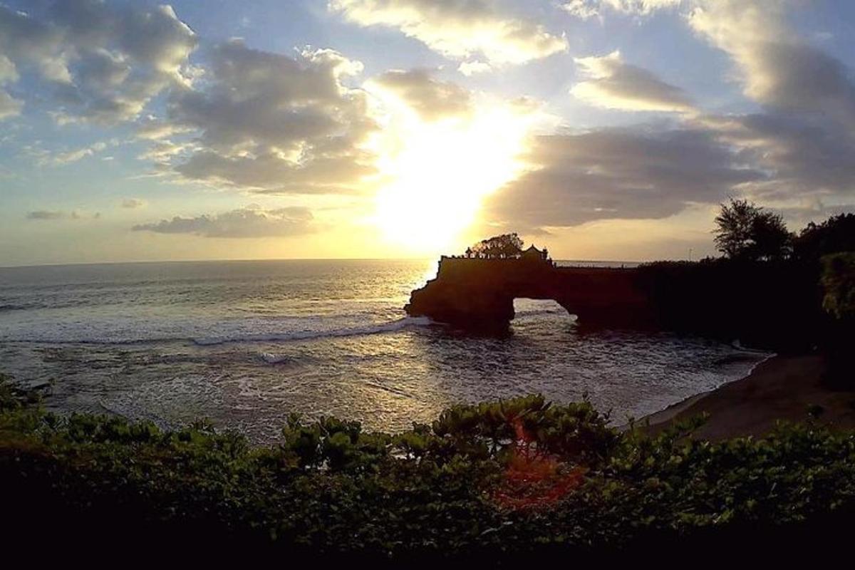 a sun setting over the ocean with a bridge