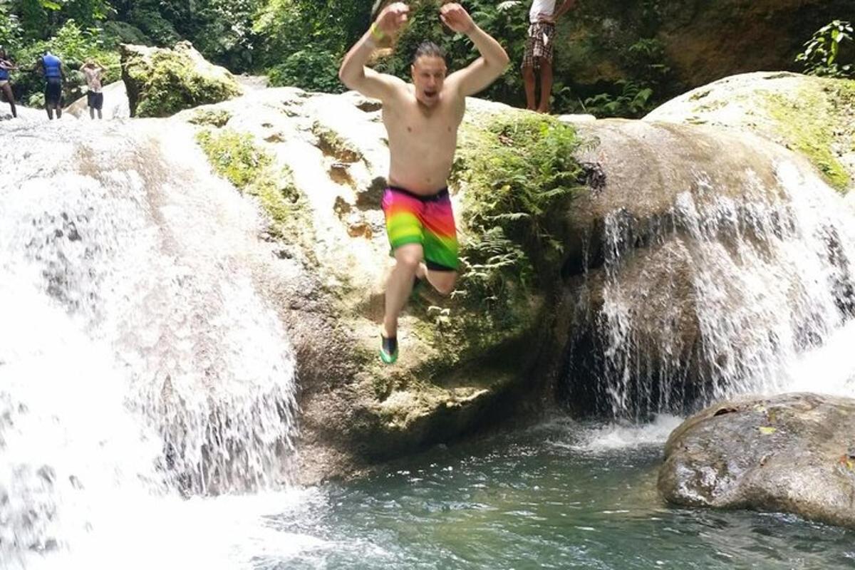 a man jumping off of a waterfall into the water