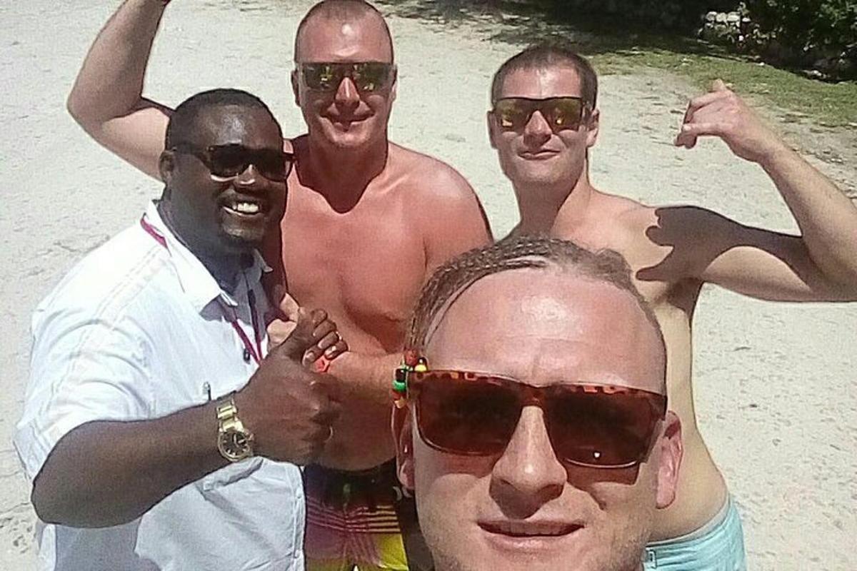 a group of three men standing on the beach