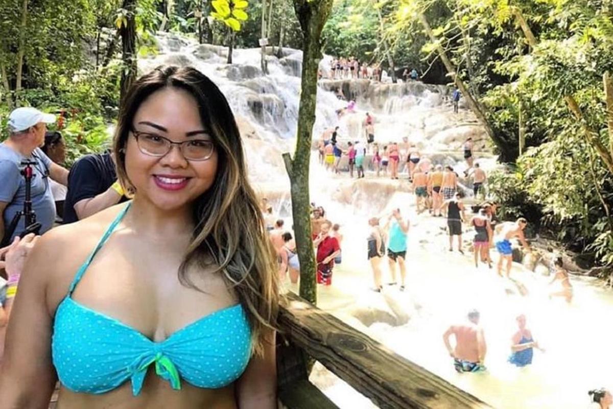 một người phụ nữ mặc bộ bikini màu xanh đứng trước thác nước