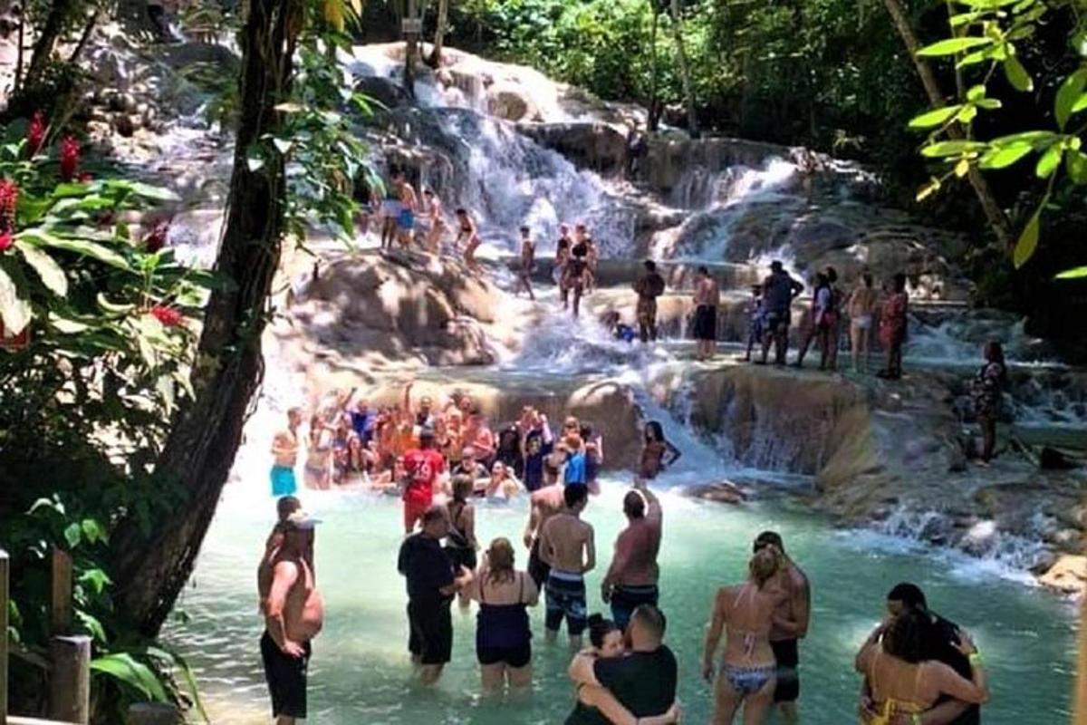 a group of people in the water at a waterfall