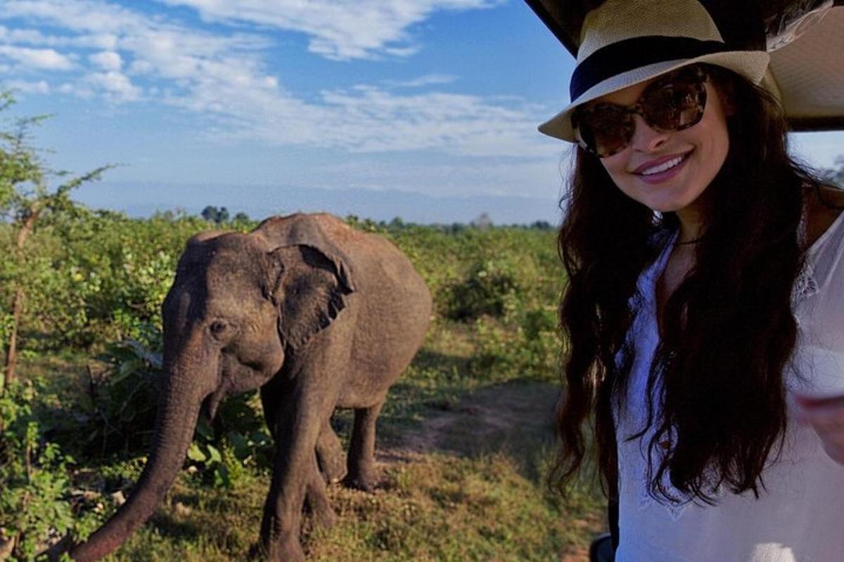 una donna con un cappello in piedi accanto a un cucciolo di elefante