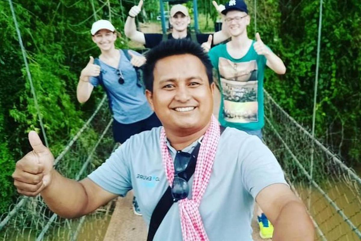seorang lelaki memberikan ibu jari di atas jambatan gantung