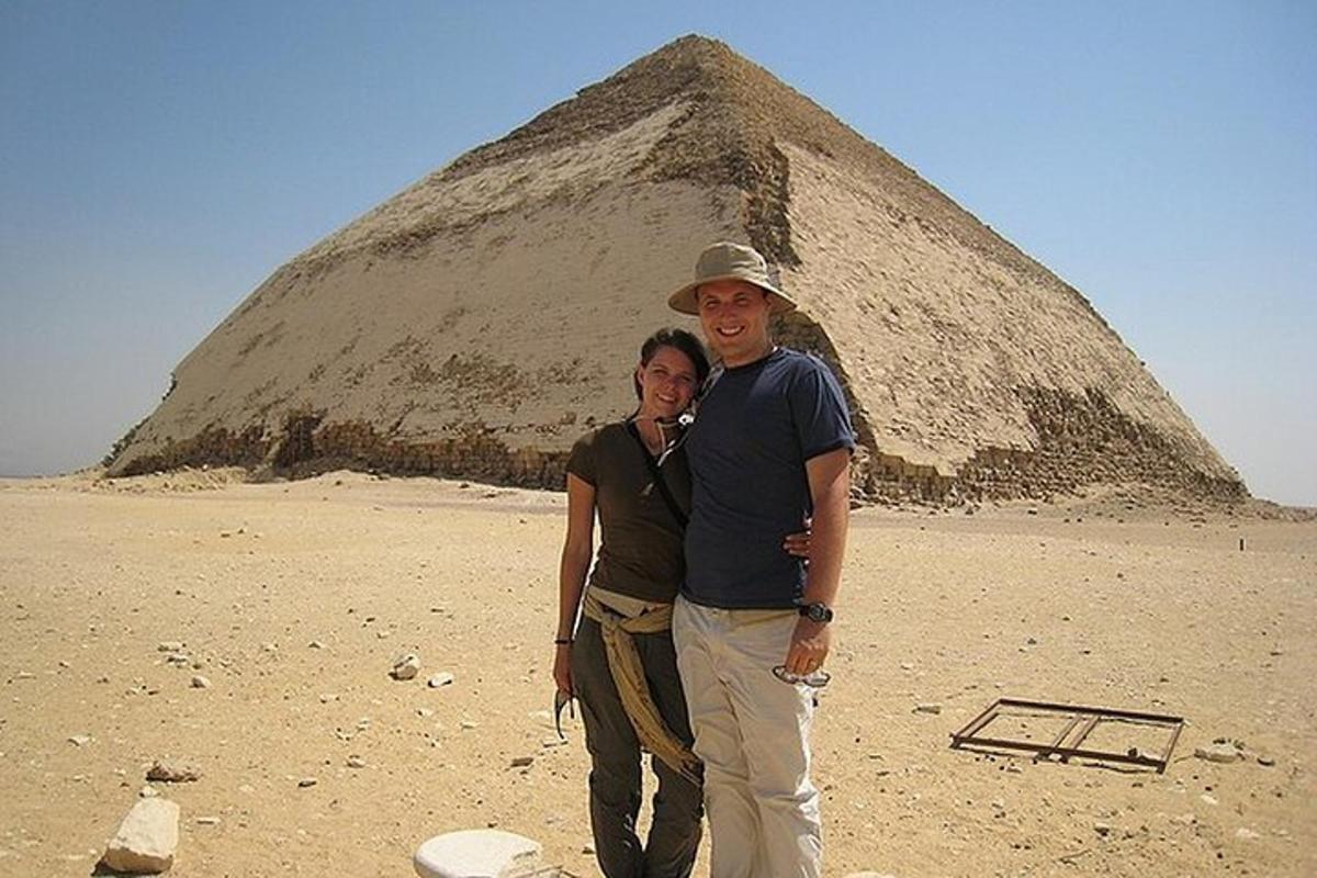 un uomo e una donna in piedi davanti a una piramide