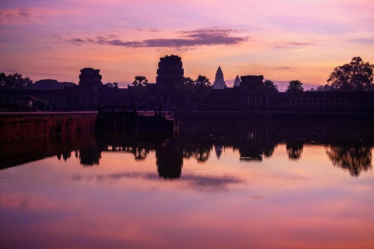um pôr do sol sobre um lago em frente a um templo