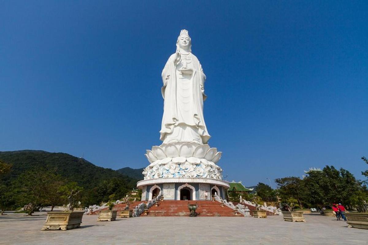 một bức tượng lớn trong công viên có những chiếc ghế dài ở phía trước