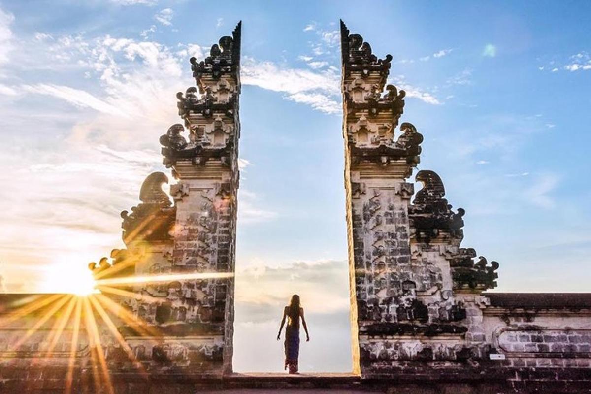 um homem passando por um portão ao pôr do sol