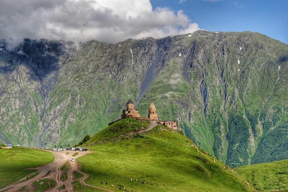 un edificio in cima a una collina verde con una montagna