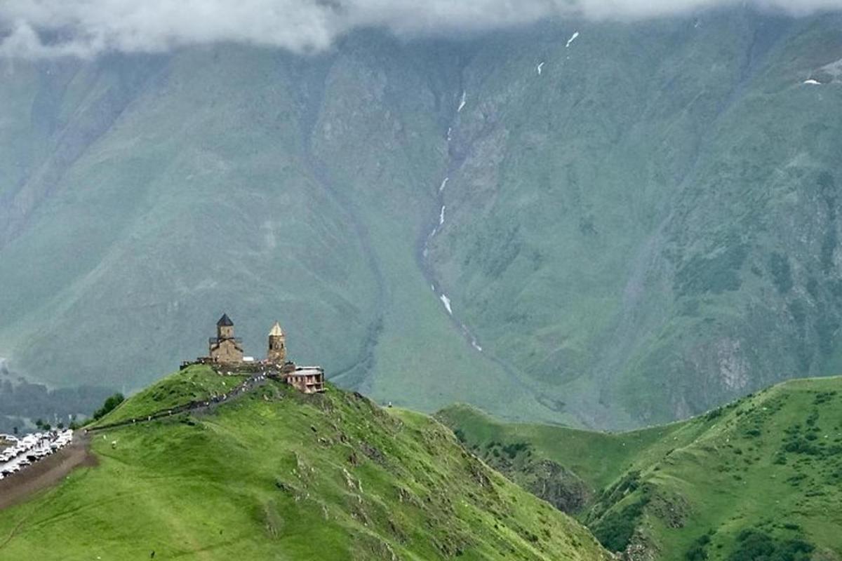 una casa in cima a una collina verde con le montagne sullo sfondo