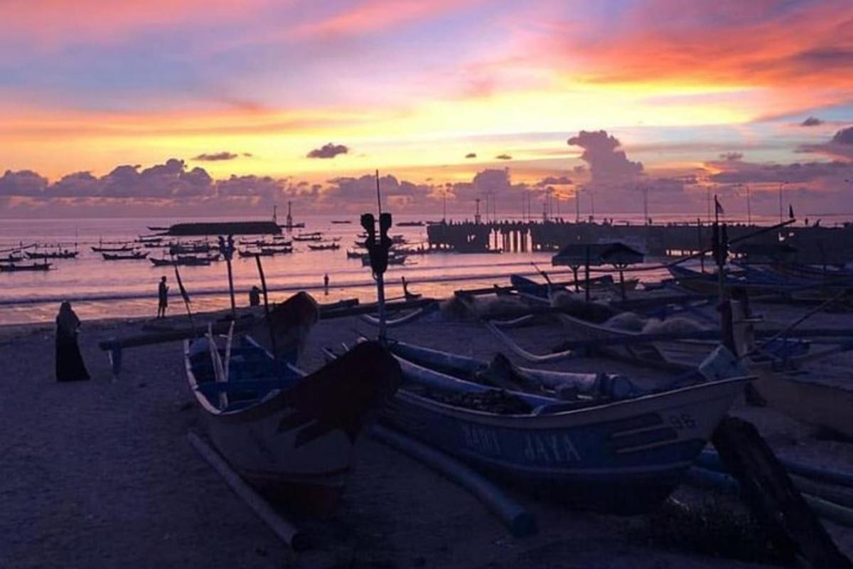 un gruppo di barche sedute sulla spiaggia al tramonto