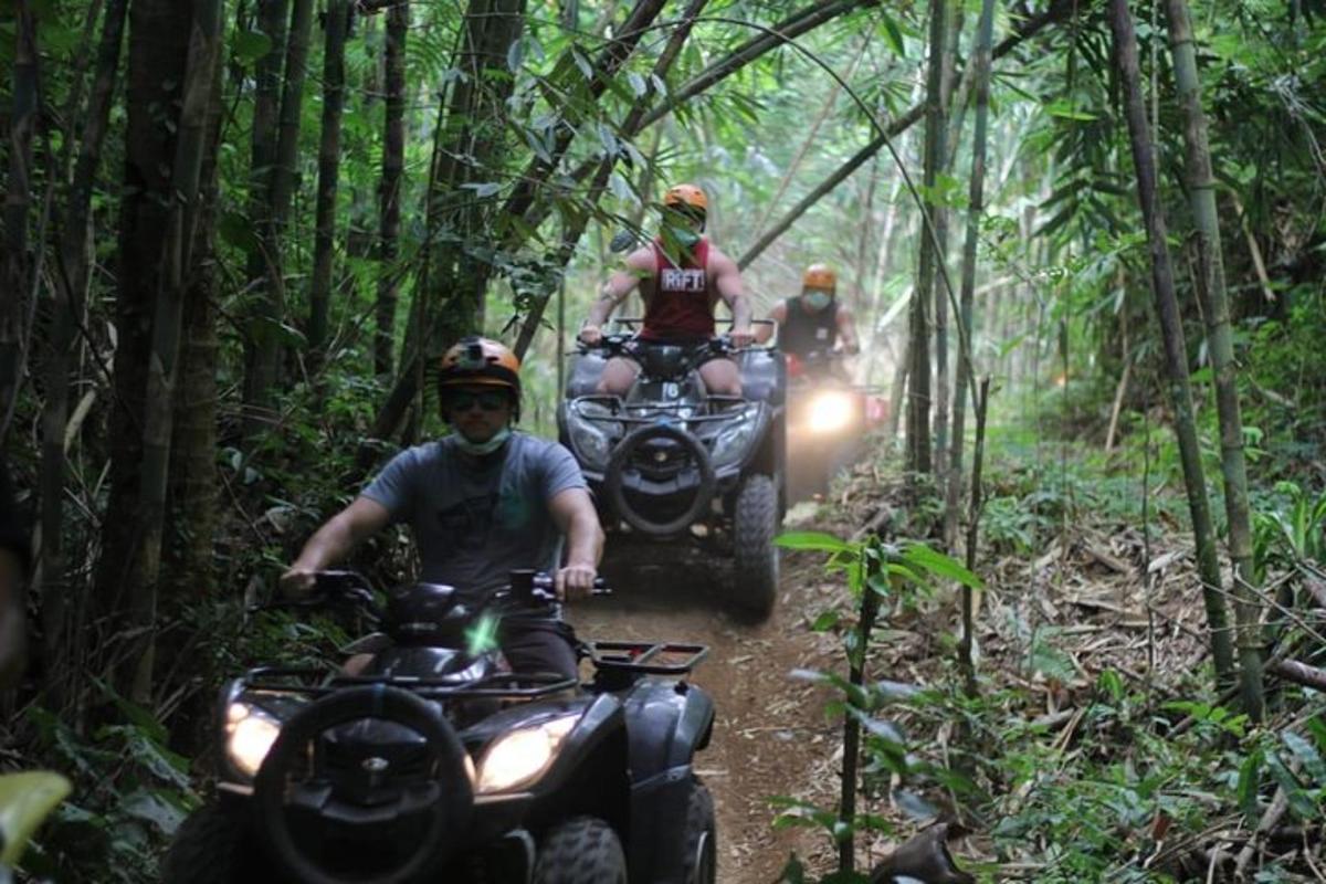 tre persone in sella a quad su un sentiero nella foresta