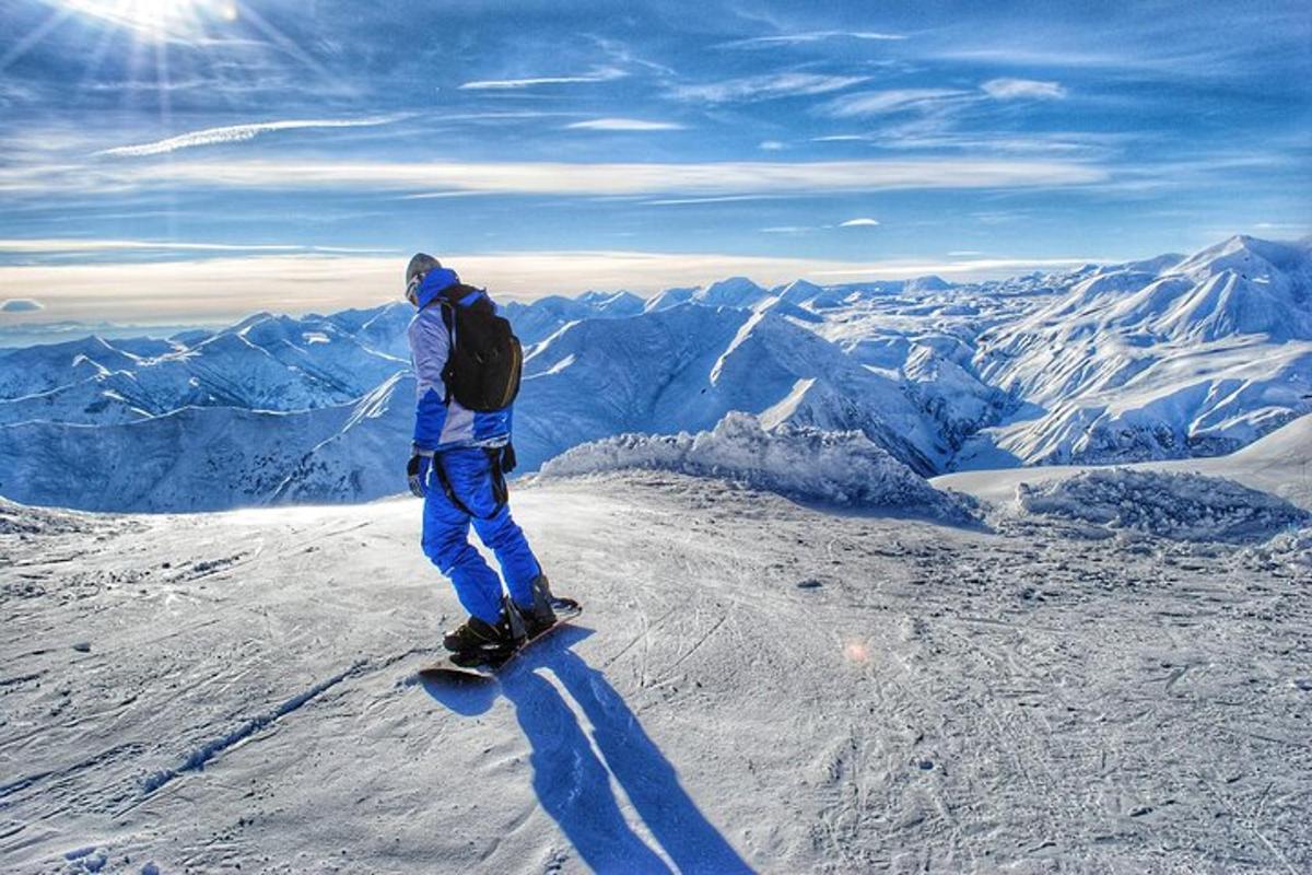 un bărbat care călărește un snowboard pe vârful unui munte