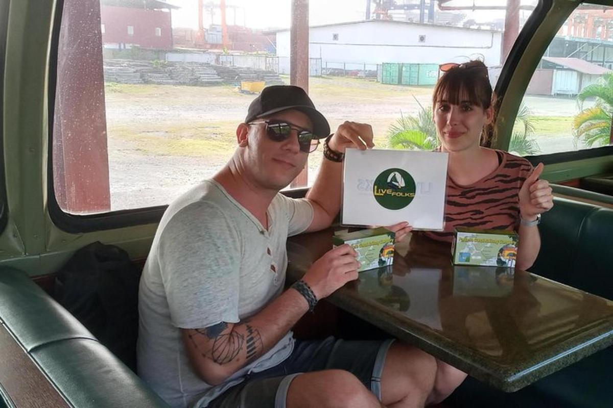 Un hombre y una mujer sentados en una mesa con un cartel.