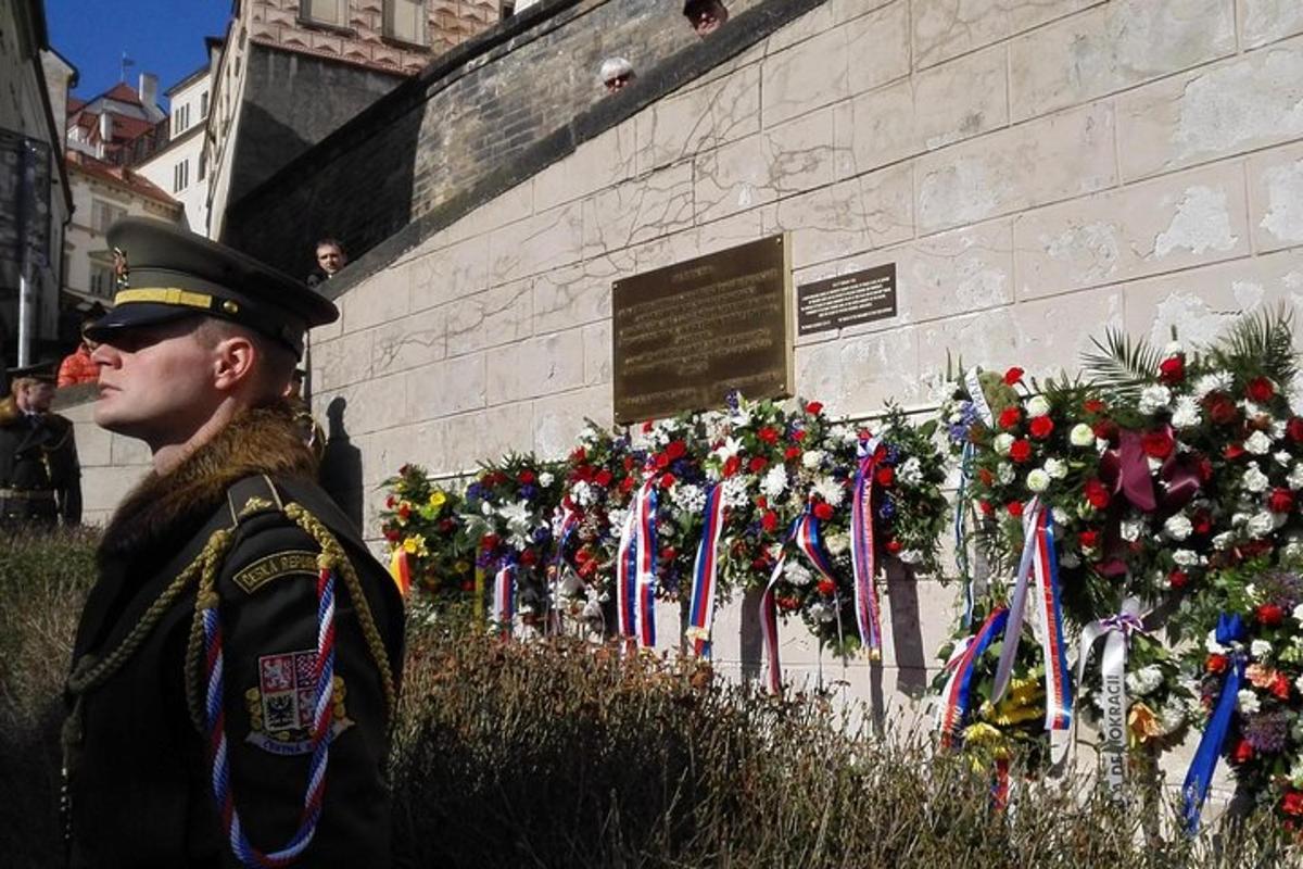 moški v uniformi stoji pred vojnim spomenikom