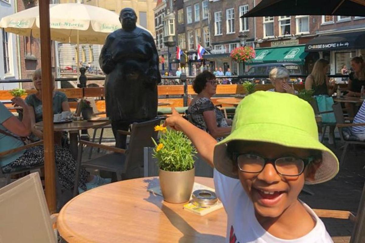 a young boy wearing a green hat standing in front of a statue