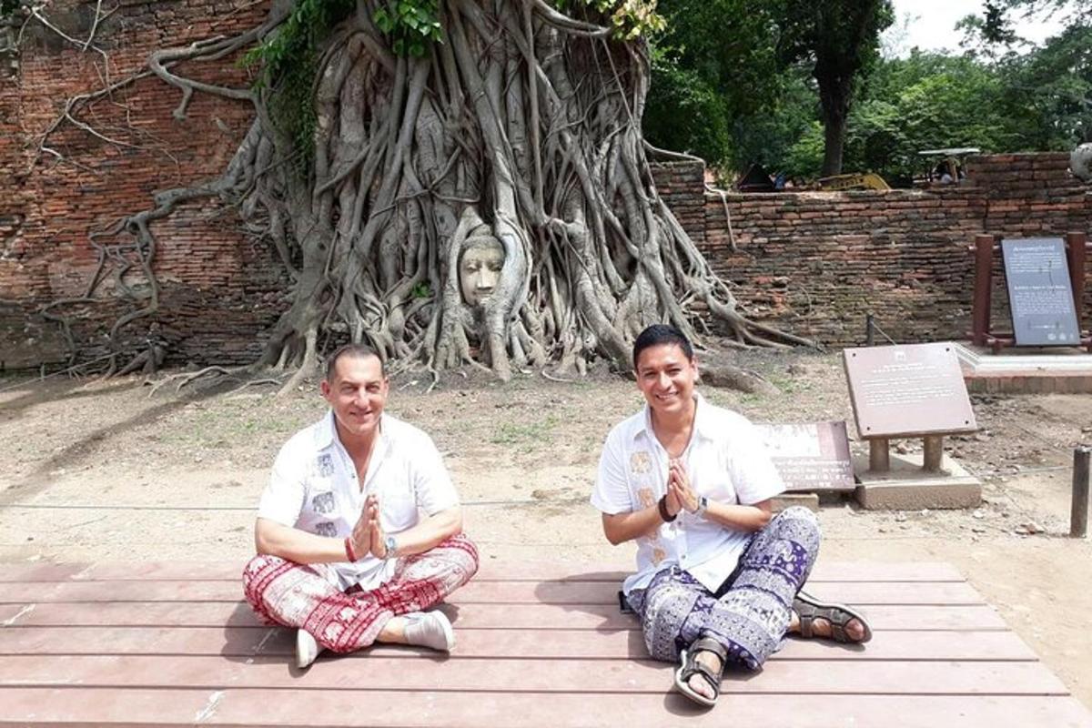 two people sitting on the ground in front of a tree