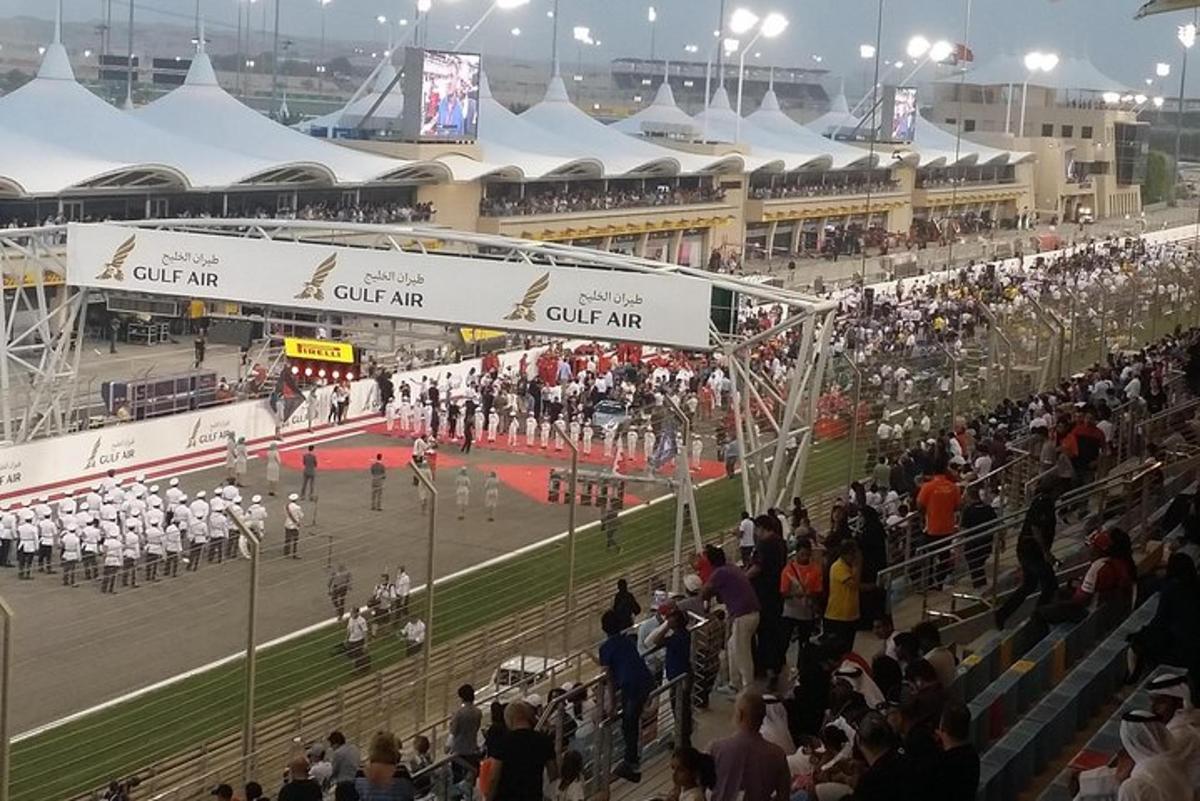 uma grande multidão de pessoas em pé ao redor de uma pista de corrida
