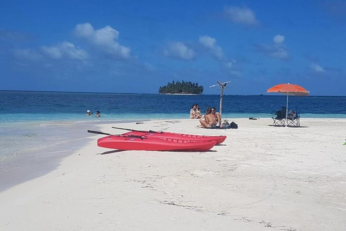 una barca rossa su una spiaggia con persone in acqua