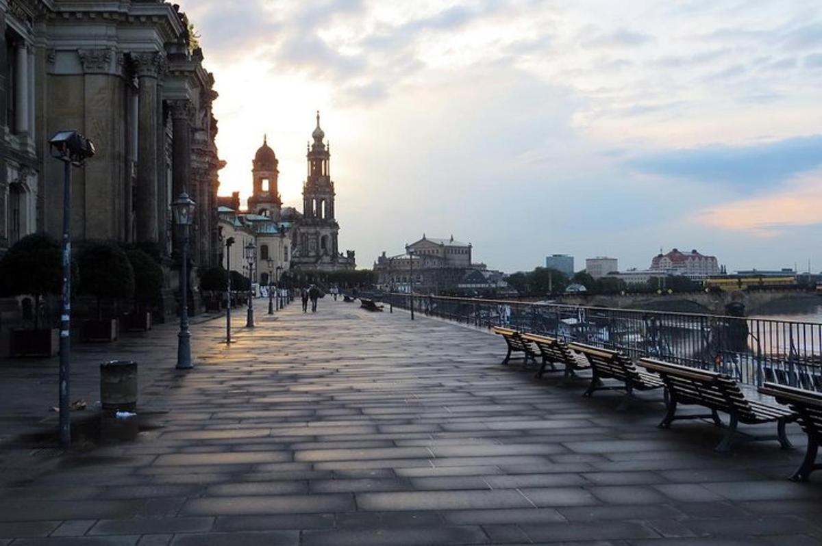 Una calle de la ciudad con bancos y edificios y una torre de reloj