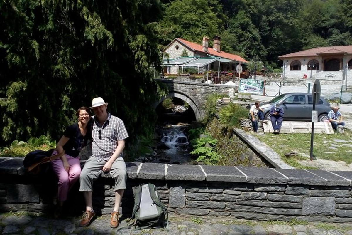 un bărbat și o femeie așezați pe un zid de piatră lângă un pod