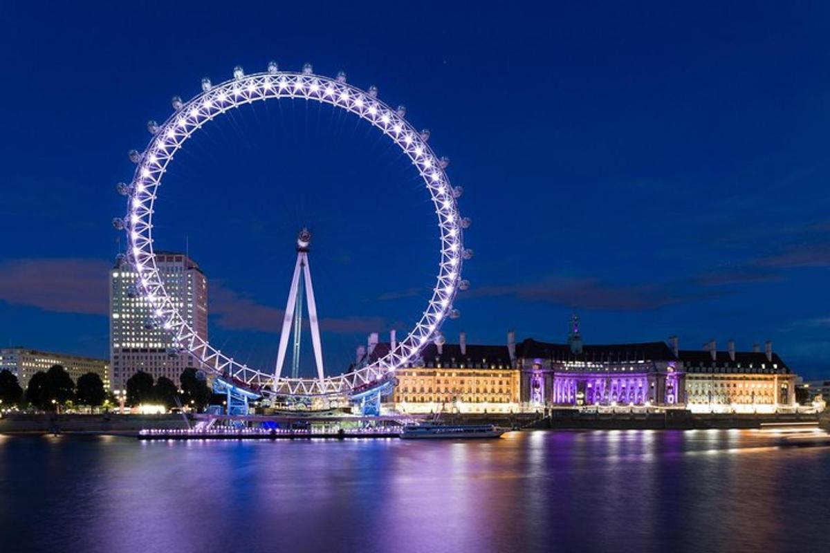 London Eye diterangi pada malam hari dengan gedung-gedung