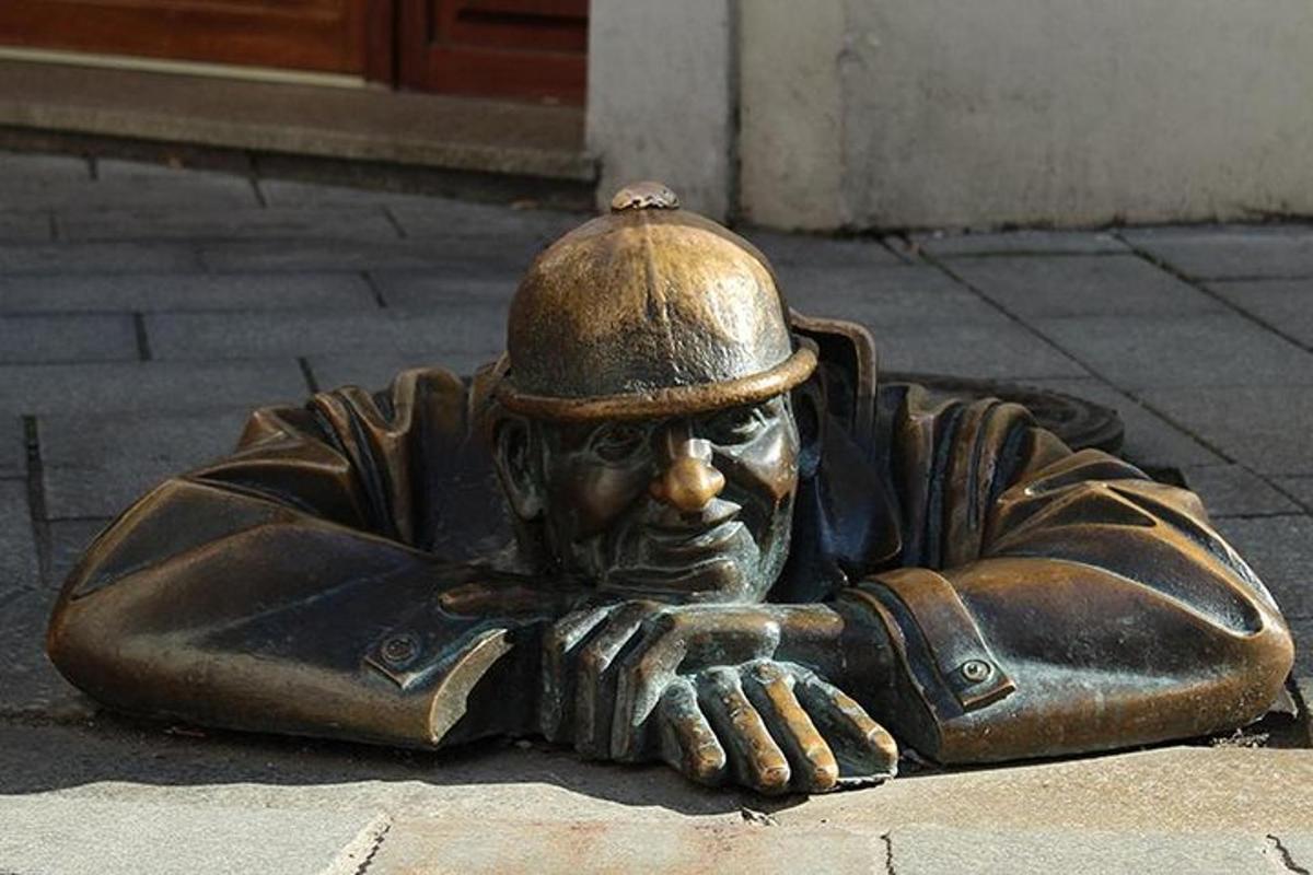 en bronsestatue av en mann med hatt