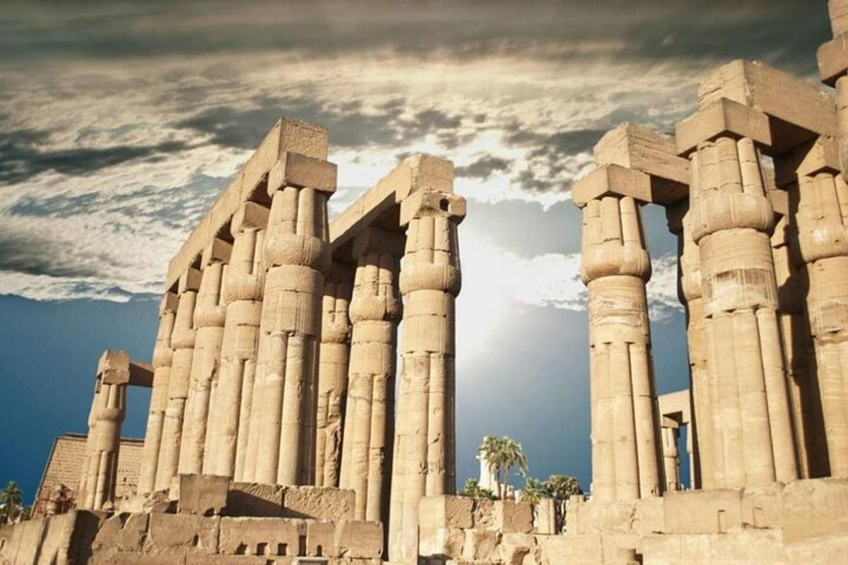 an ancient building with columns and a cloudy sky