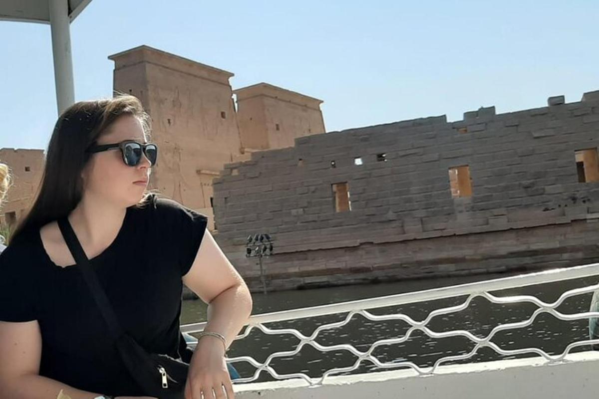 uma mulher de óculos de sol sentada em uma saliência