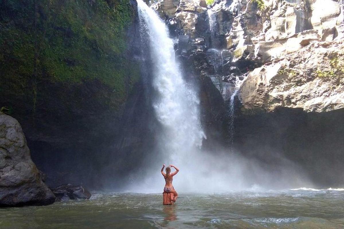 una dona dempeus a l'aigua davant d'una cascada