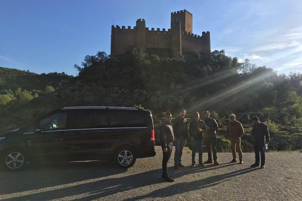 um grupo de pessoas em pé ao lado de uma van em frente a um castelo