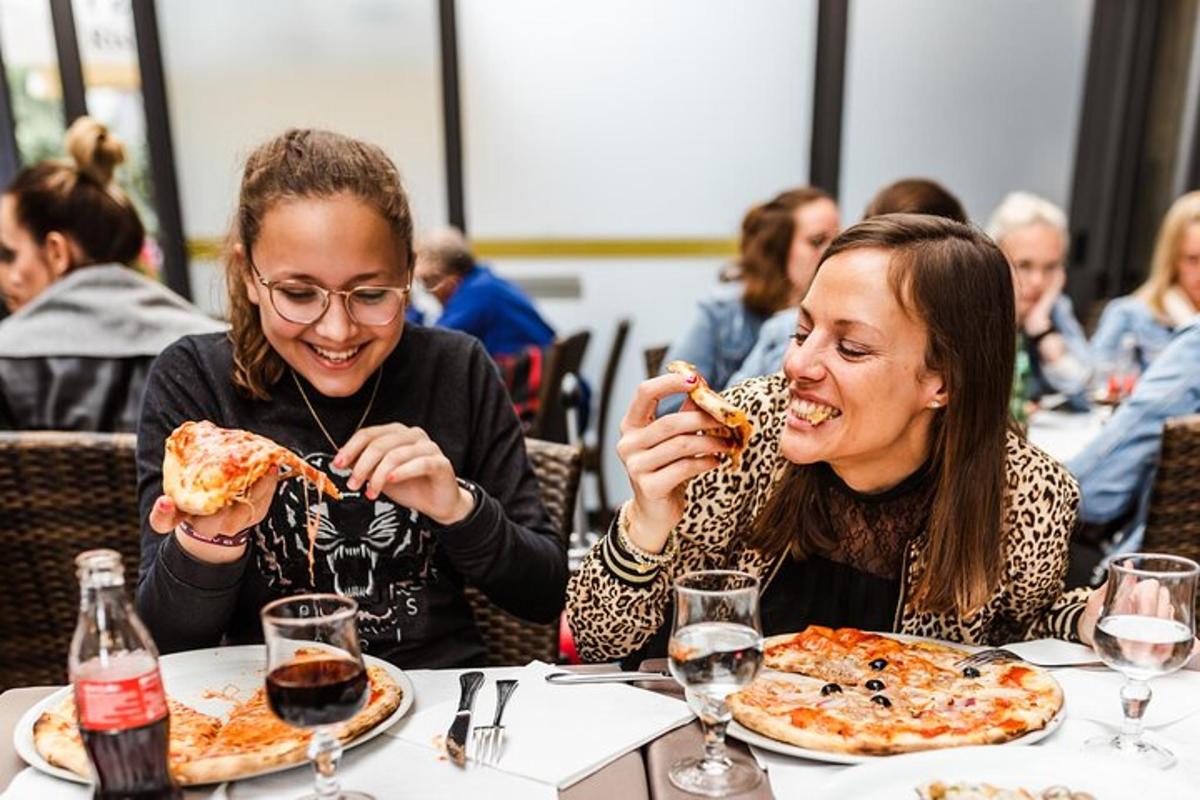 dua wanita duduk di meja makan pizza