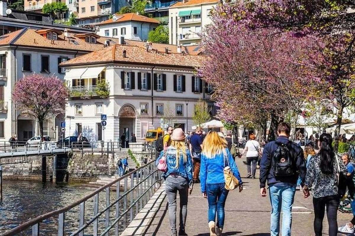 Un grupo de personas caminando por una acera junto a un río.