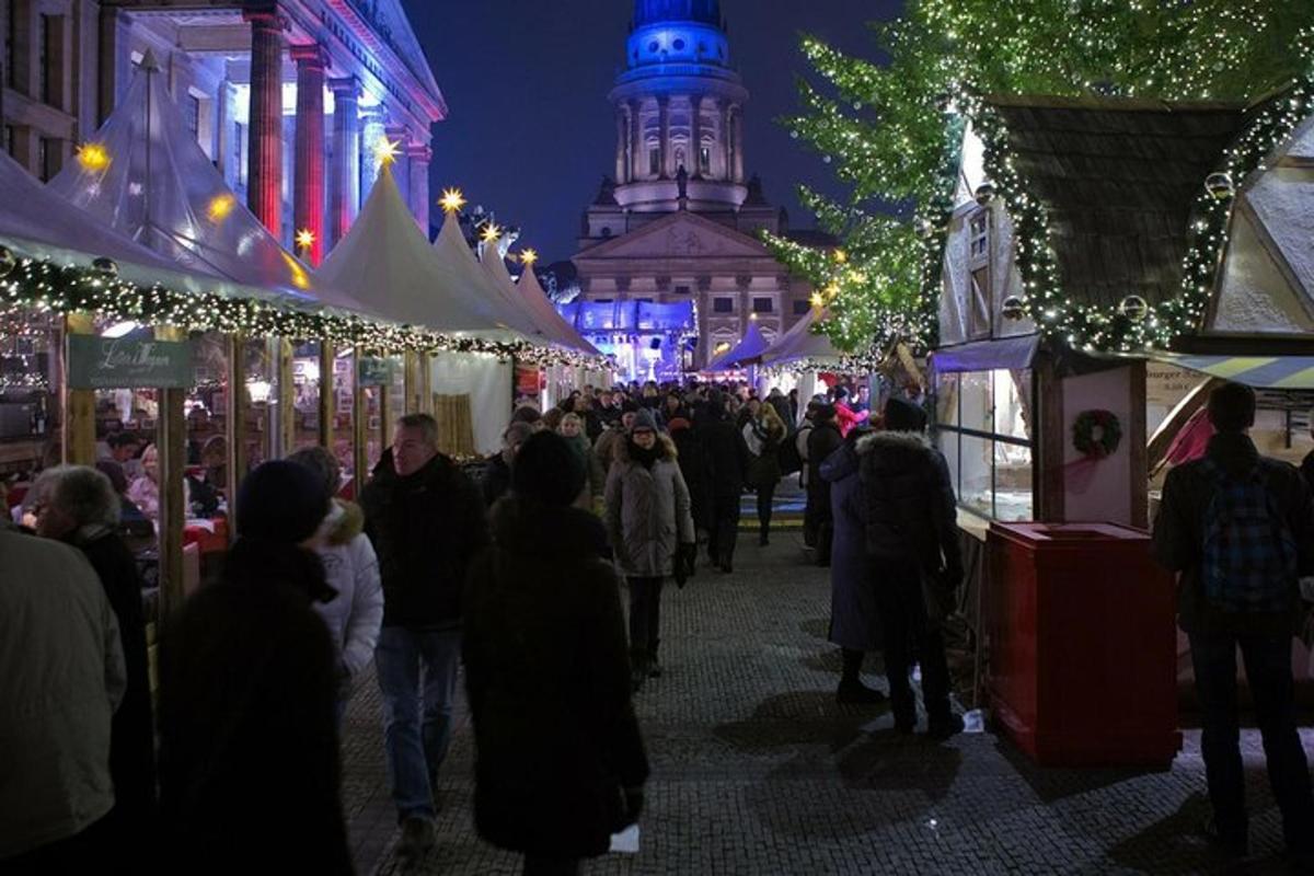 uma multidão de pessoas caminhando por um mercado de natal à noite