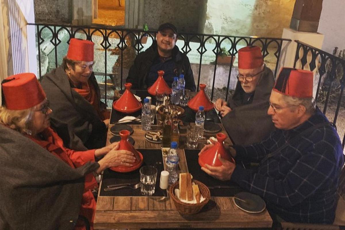 μια ομάδα ανθρώπων που κάθονται γύρω από ένα τραπέζι φορώντας καπέλα