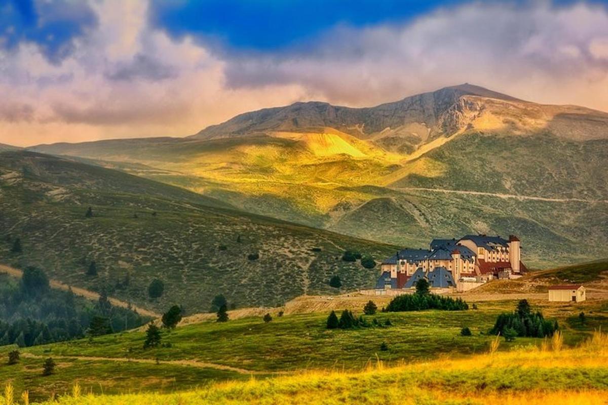 uma casa em uma colina com montanhas ao fundo