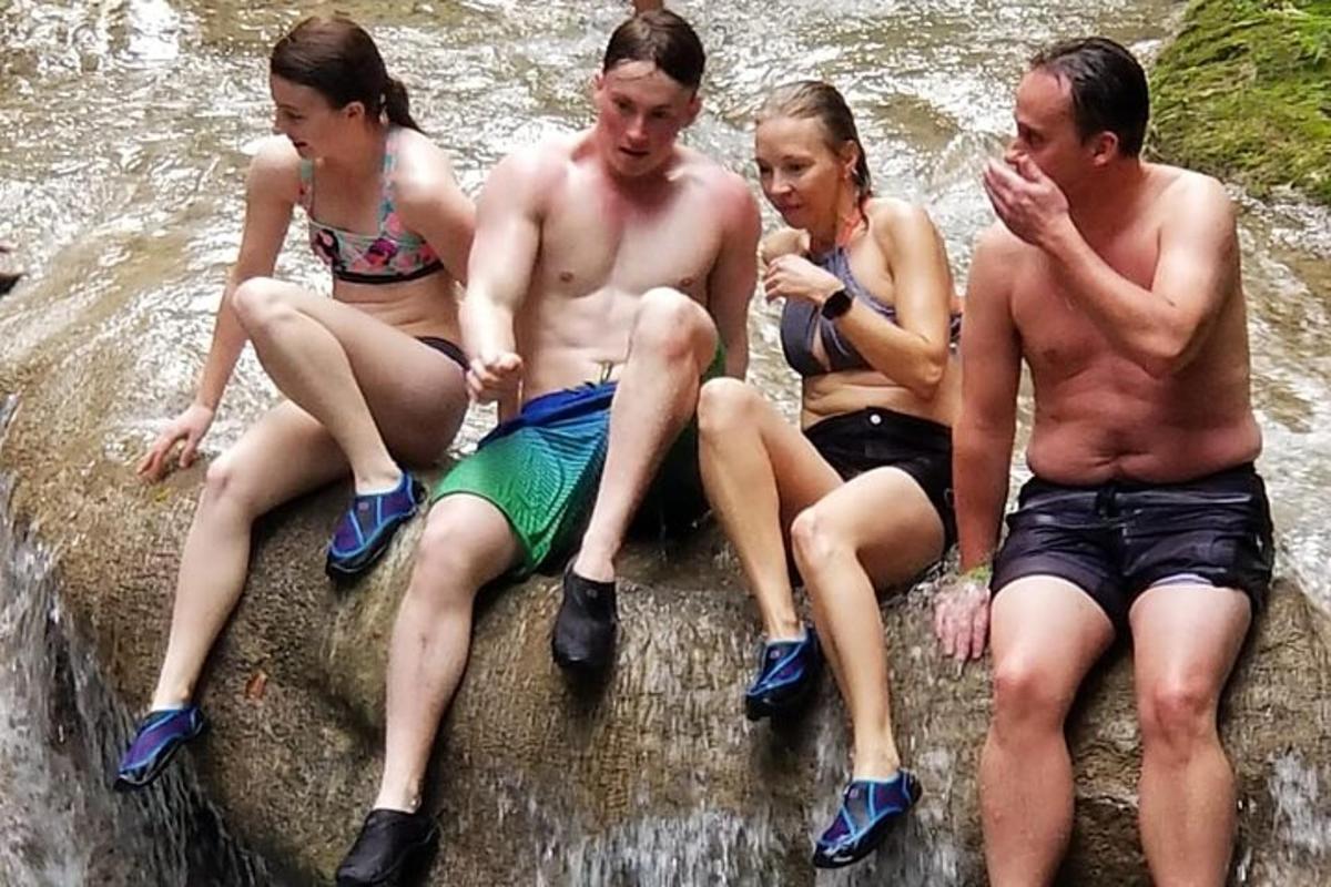 a group of people sitting on a rock in the water
