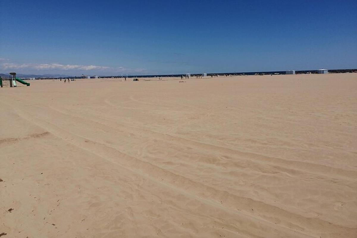 uma praia vazia com pessoas caminhando na areia