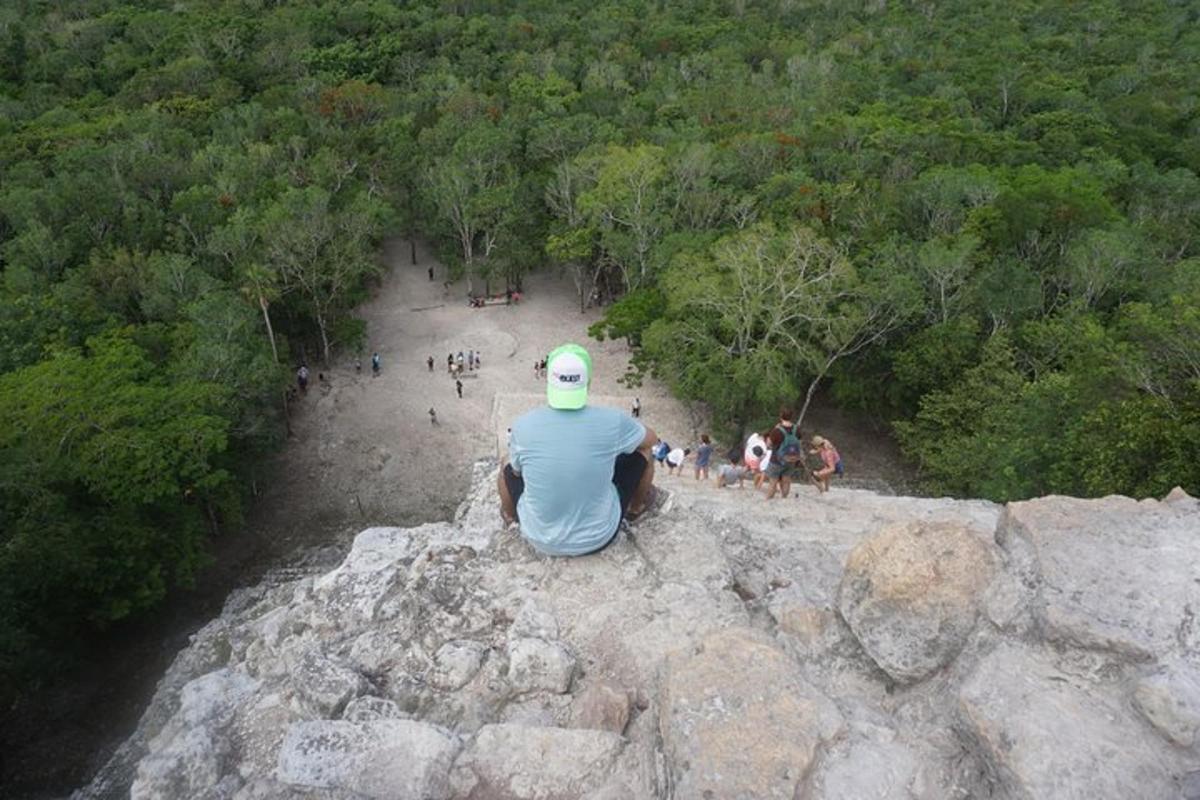 seorang pria duduk di tepi gunung